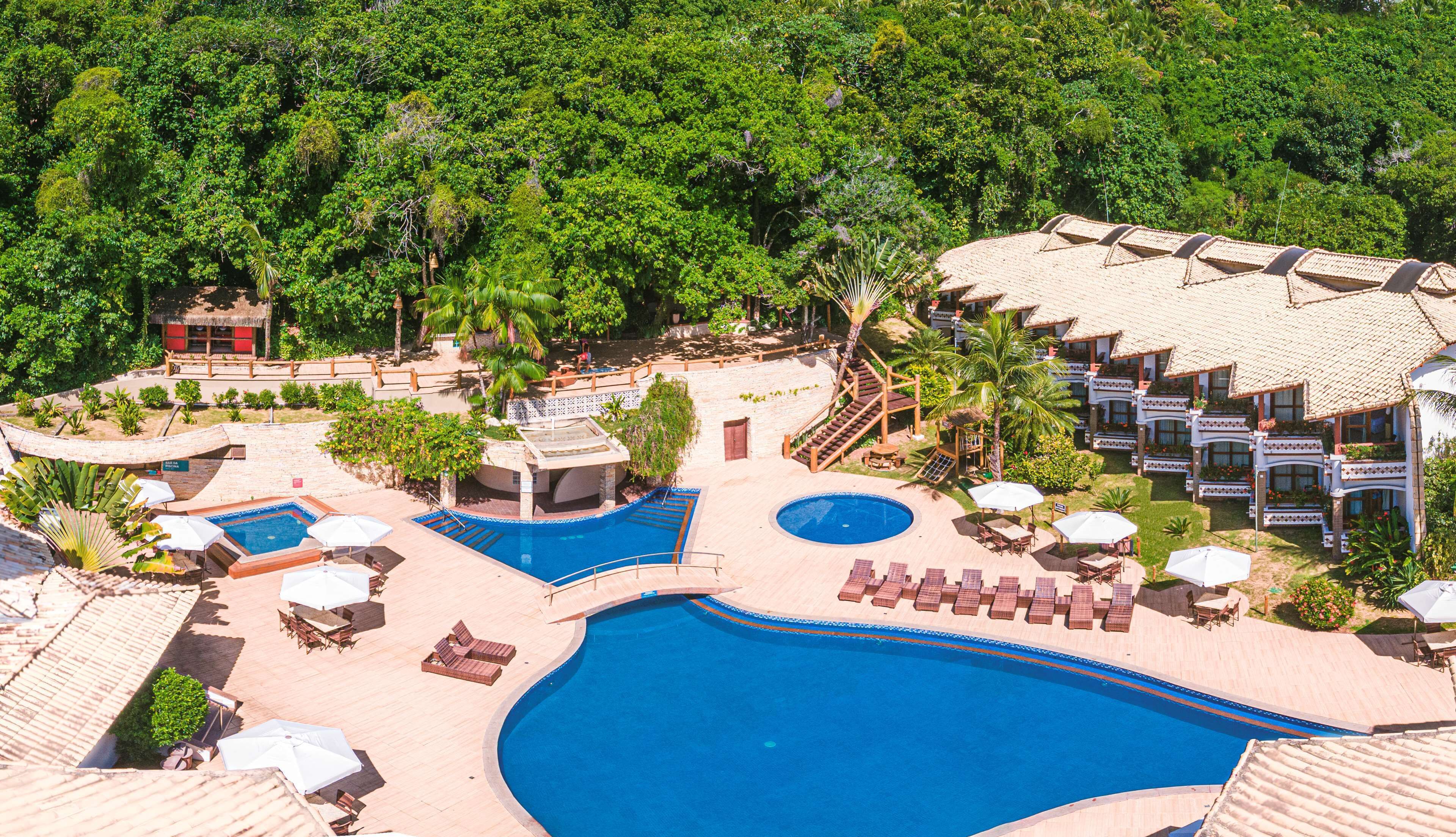 A resort with multiple swimming pools, outdoor seating, and lush greenery.