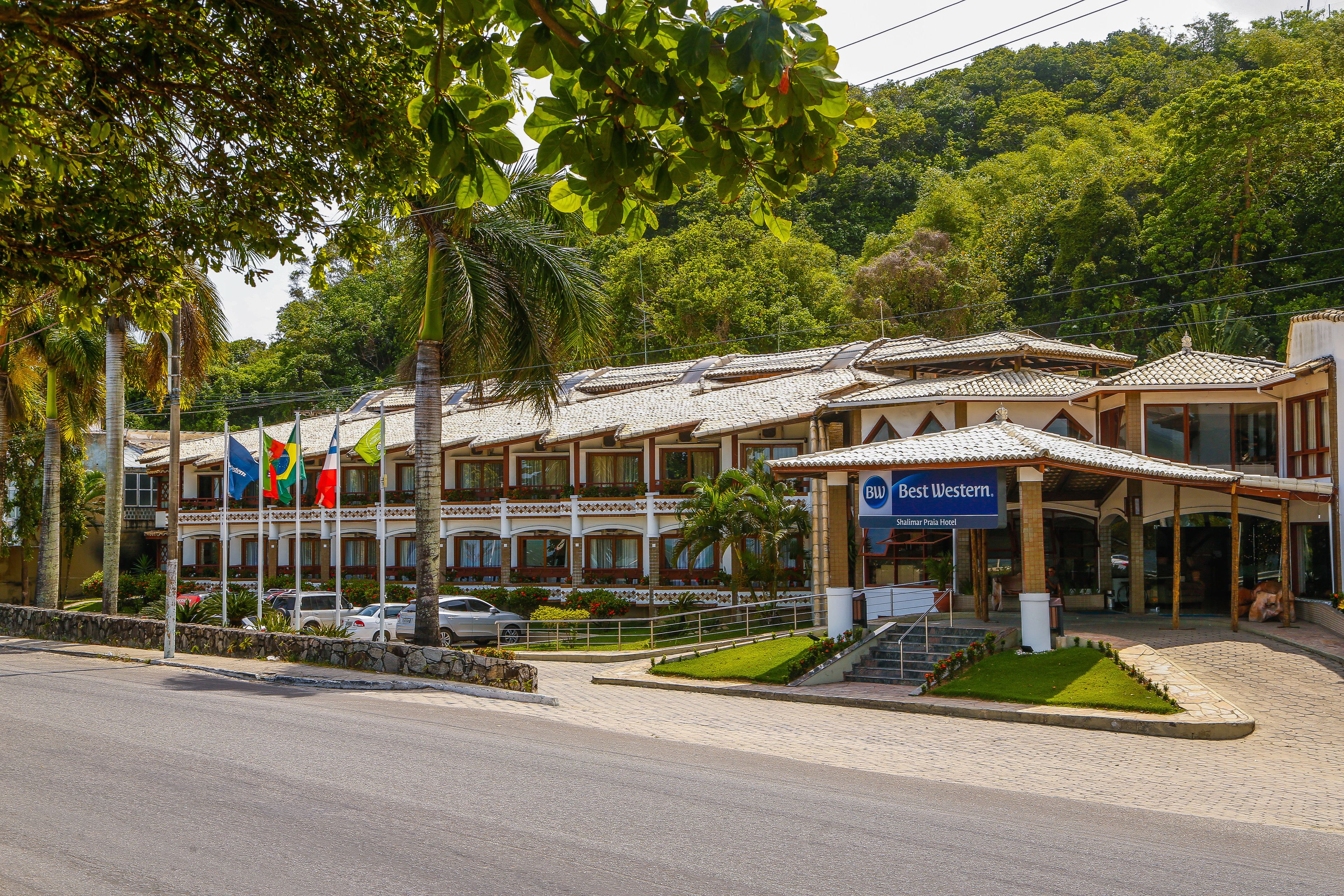 A hotel with multiple balconies, a covered entrance, and a landscaped garden.