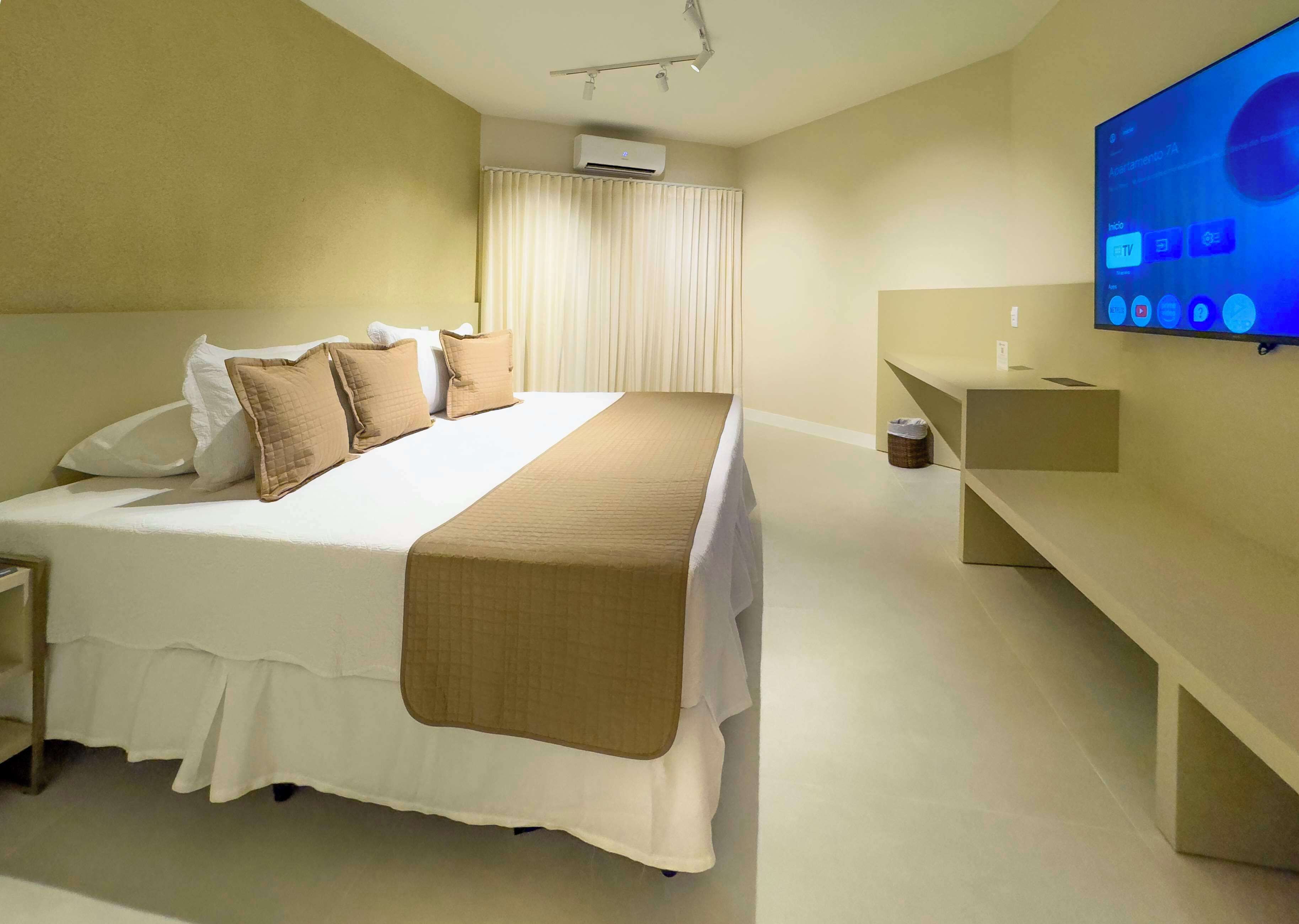 Une chambre d’hôtel moderne avec un grand lit, une table de chevet, une télévision et un banc.