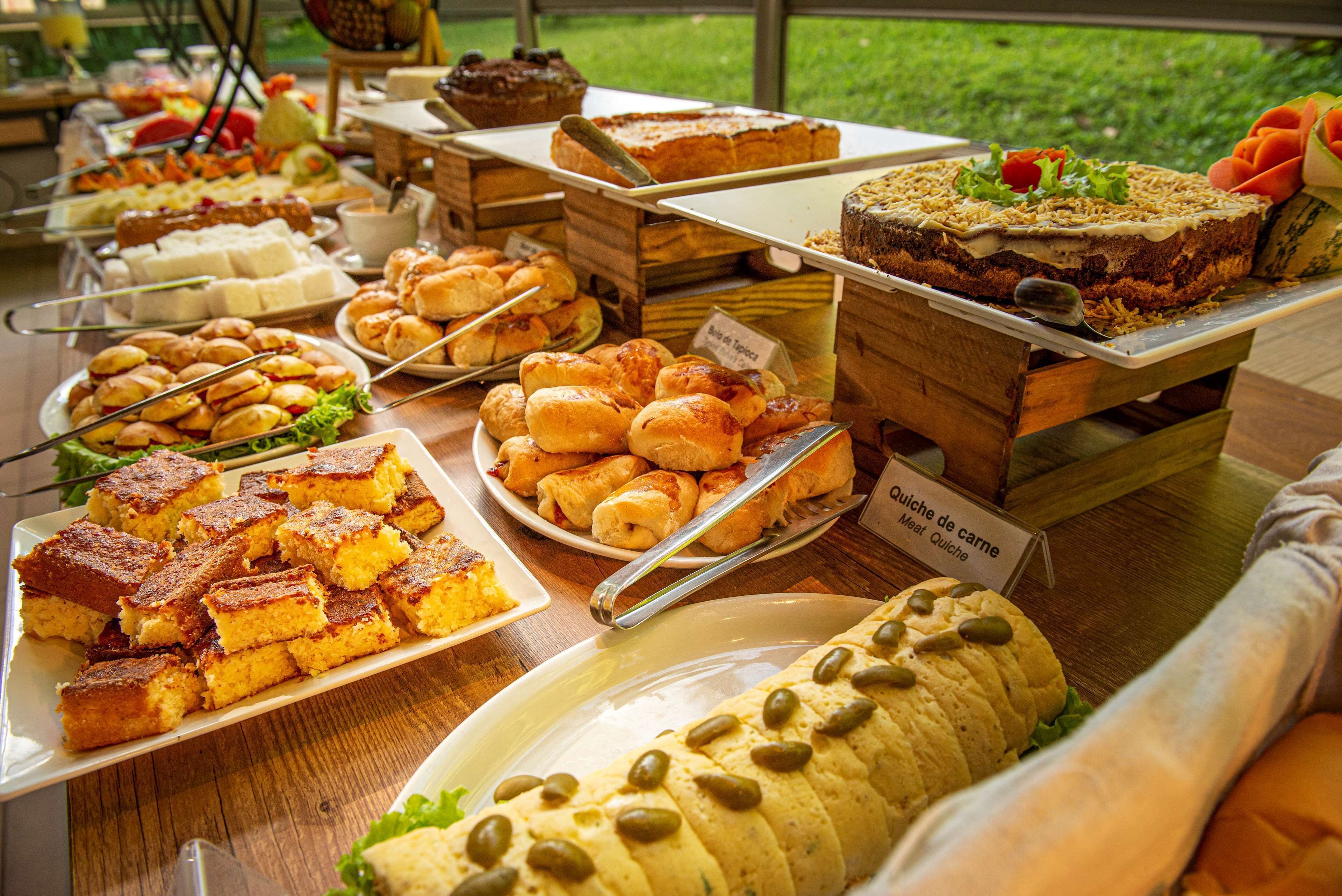 Un bufé con diversos alimentos, incluyendo pasteles, bollería y un gran plato de carne.