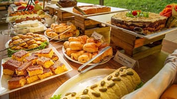 Un bufé con diversos alimentos, incluyendo pasteles, bollería y un gran plato de carne.