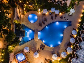 A large, circular swimming pool surrounded by lounge chairs and umbrellas, with a staircase leading to an upper level. - Best Western Shalimar Praia Hotel (Porto Seguro)