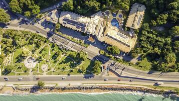 Vista aérea de un complejo turístico en la costa con piscina, paneles solares y playa.