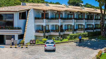 A hotel with a central entrance, multiple balconies, and a paved driveway.