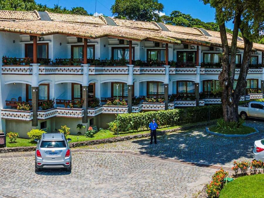 A hotel with a central entrance, multiple balconies, and a paved driveway.