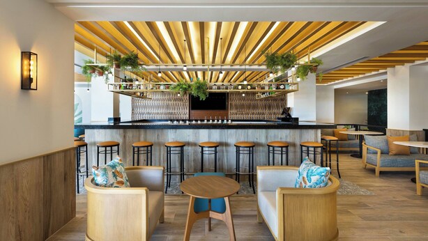 Un espace bar moderne avec des lambris en bois au plafond, des tabourets de bar et différents types de sièges.