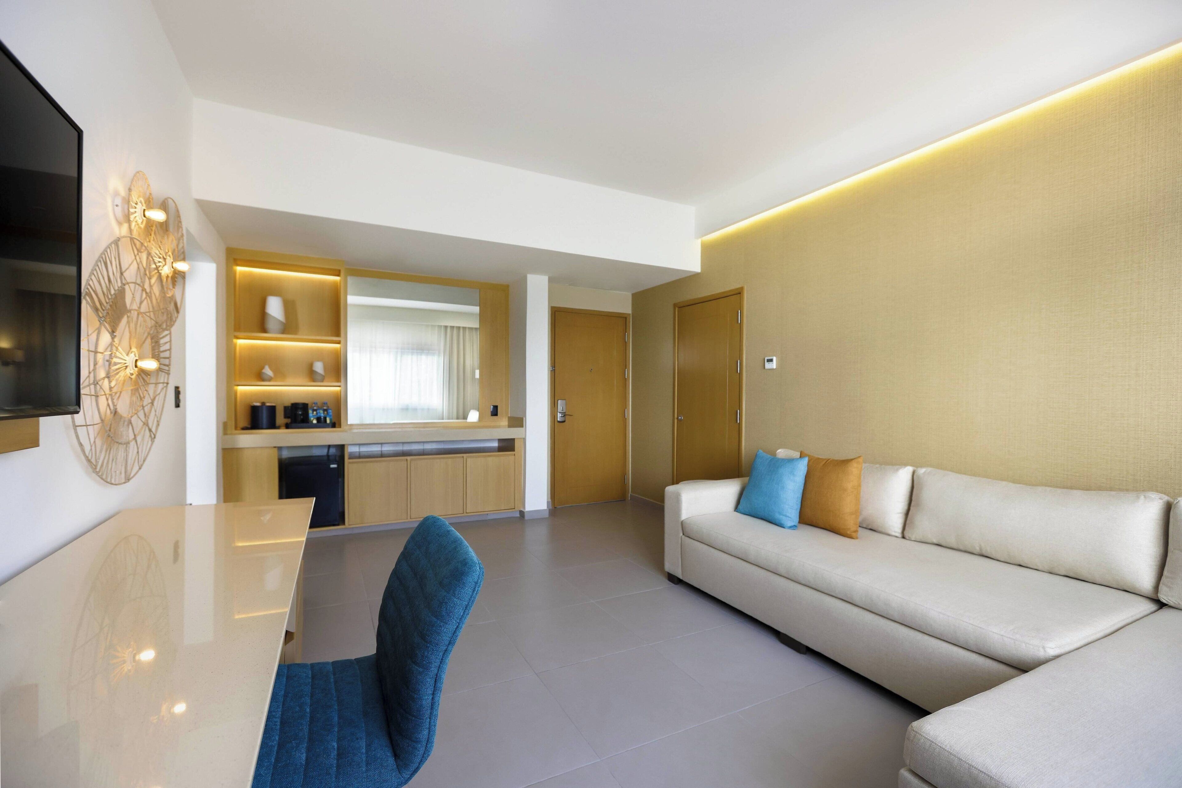 A modern living room with a sofa, a coffee table, and a TV mounted on the wall.