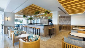 Un espace bar moderne avec un plafond en bois, des tabourets de bar et des sièges dotés de coussins.