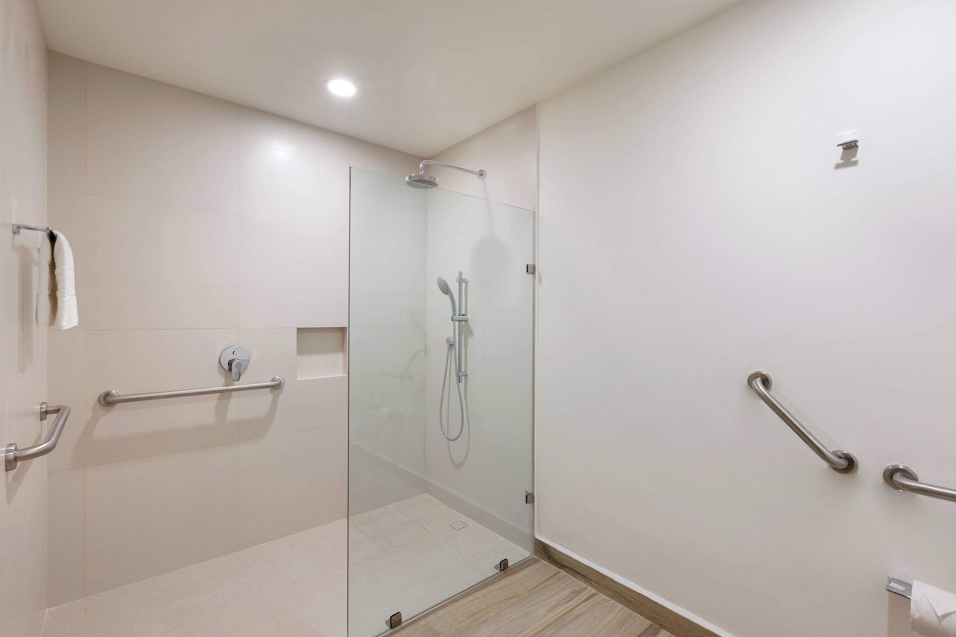 Een moderne badkamer met een glazen douchecabine, grepen en een toilet met een handgreep.