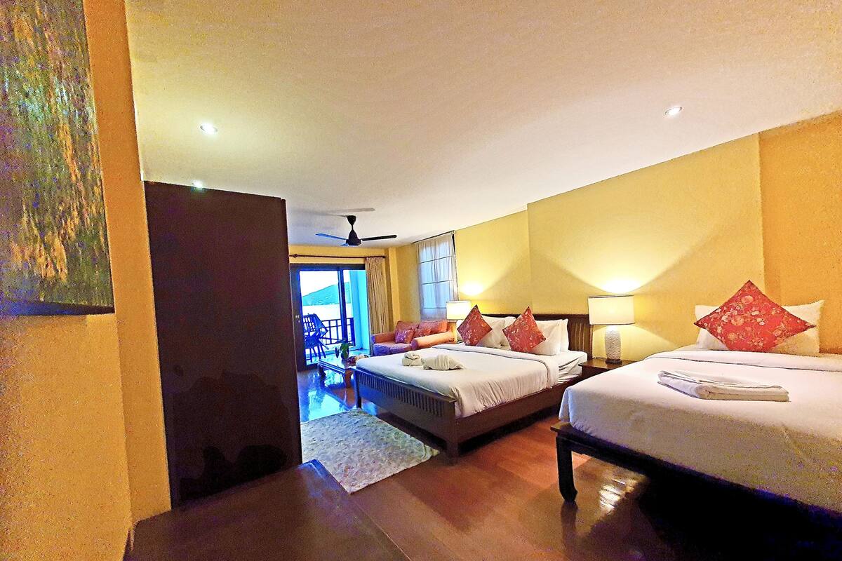 A hotel room with two beds, a ceiling fan, and a view of the outside.