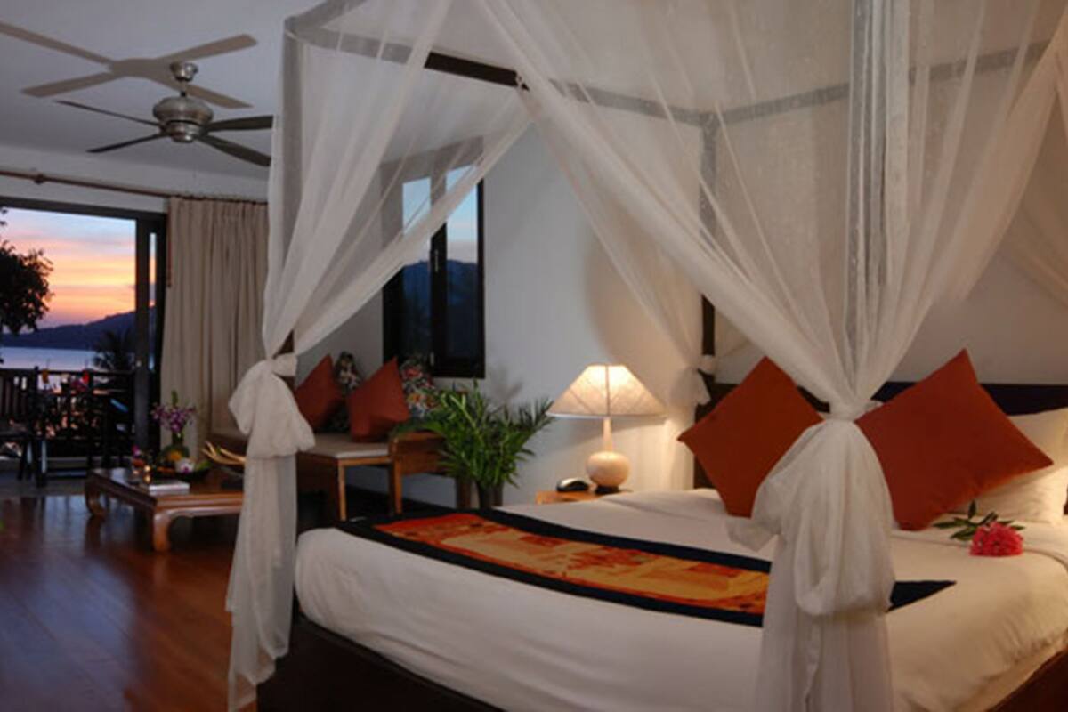 A spacious bedroom with a large bed, a ceiling fan, and a view of the outdoors.