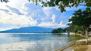 A beach with clear water, a sandy shore, and a mountain in the background. - Cinnamon Beach Villas (Koh Samui)