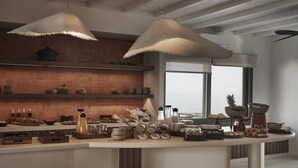 A modern kitchen with a brick backsplash, pendant lights, and a variety of food items displayed on the counter.