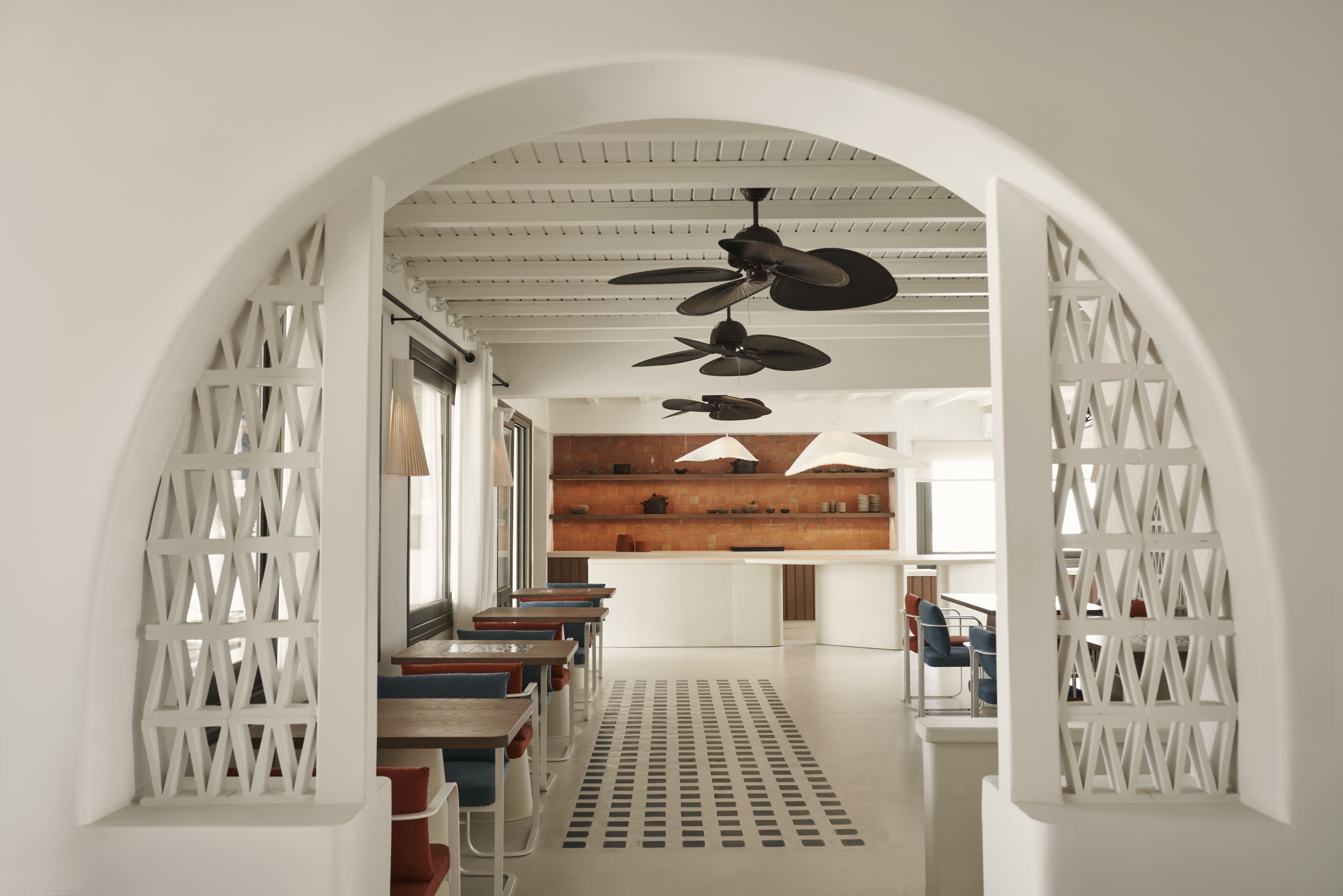 Un interno moderno con un'area salotto centrale, pareti bianche e ventilatori a soffitto.