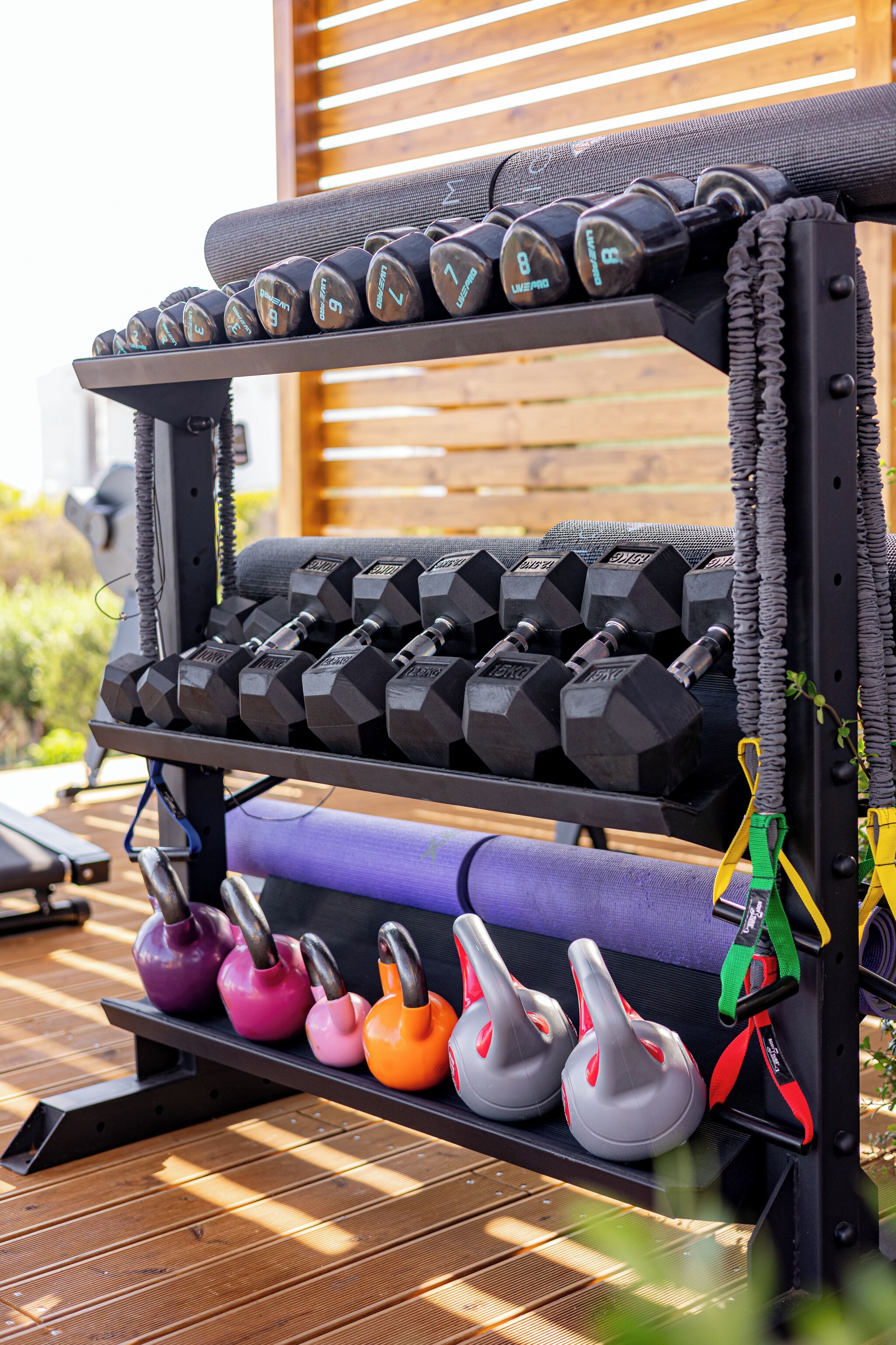 A weightlifting bench with dumbbells and kettlebells.