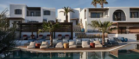 A modern resort with a pool, lounge area, and white buildings with balconies.