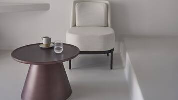 Una habitación minimalista con una mesa redonda, una silla y un cuadro abstracto colgado en la pared.