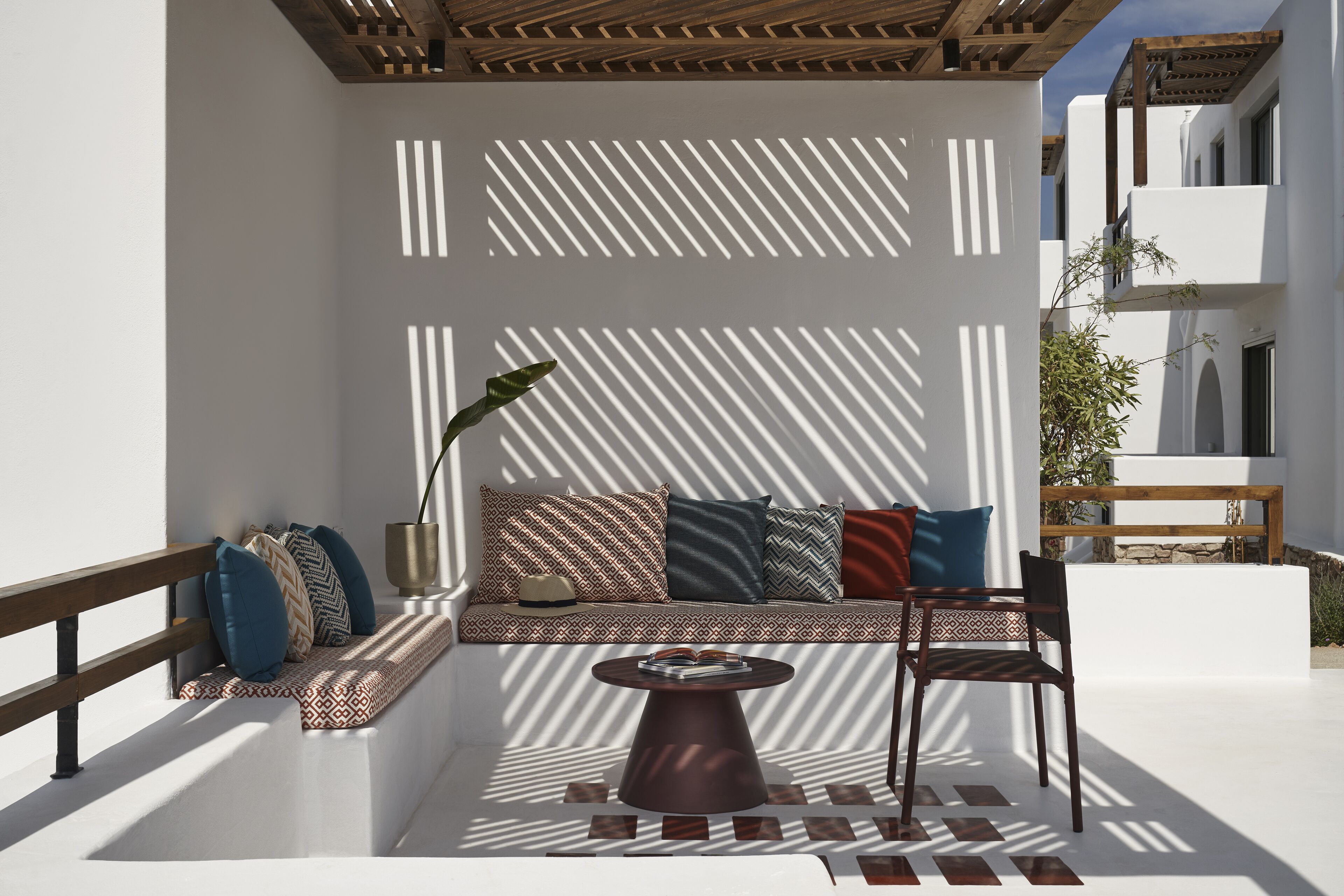 Un área de estar al aire libre con un sofá, cojines, una mesa y una silla.