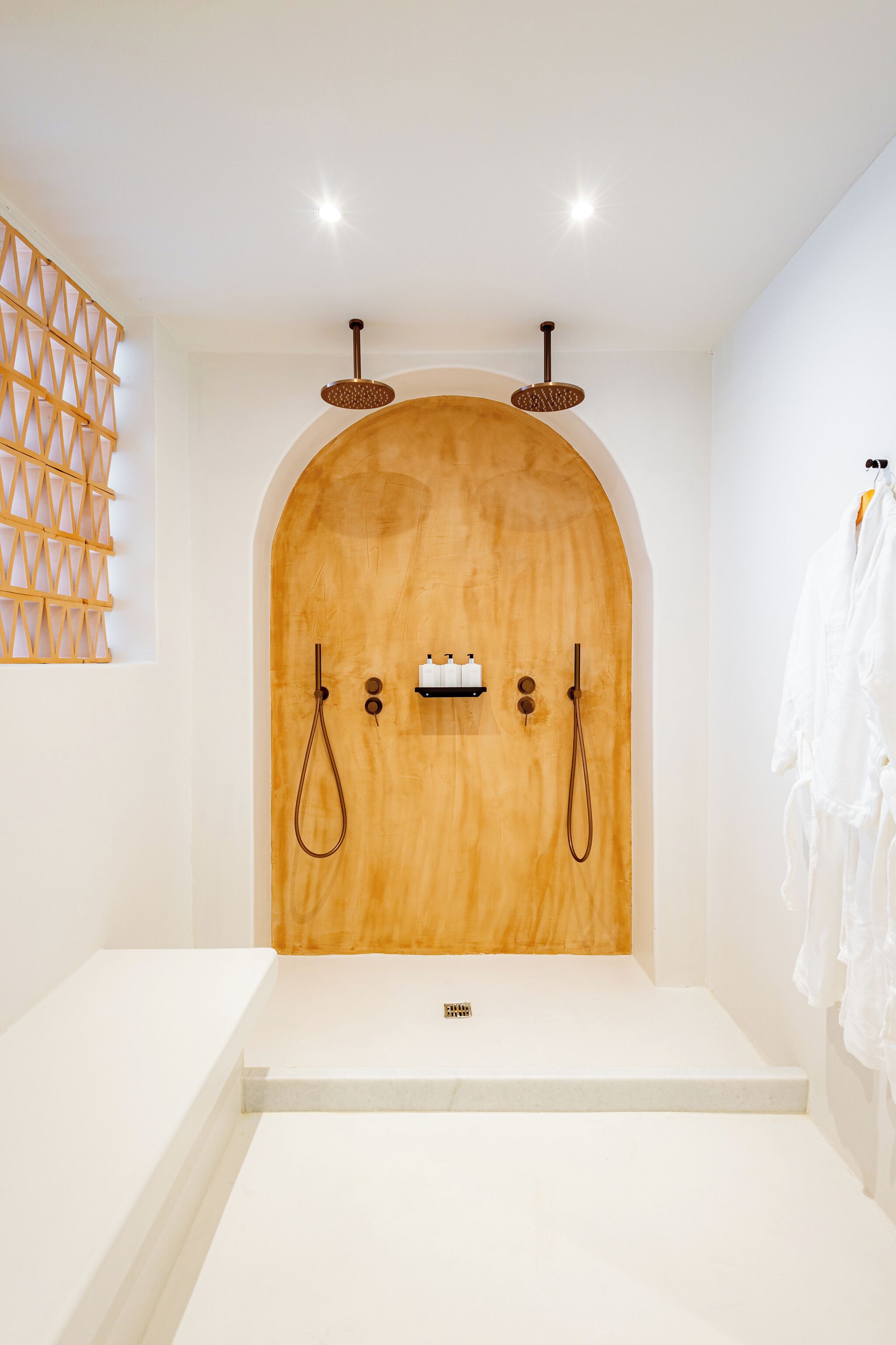 A modern bathroom with a wooden arched shower enclosure, white fixtures, and a towel rack.