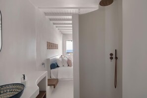A modern bathroom with a white sink, a patterned bowl, and a shower area with a view of the sea.