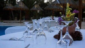 A table set for a meal with wine glasses, cutlery, and a centerpiece with flowers and a candle.