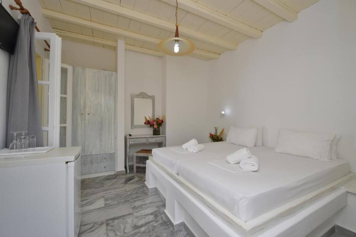 Ein Hotelzimmer mit Bett, Schreibtisch, Spiegel und einer Pendelleuchte.