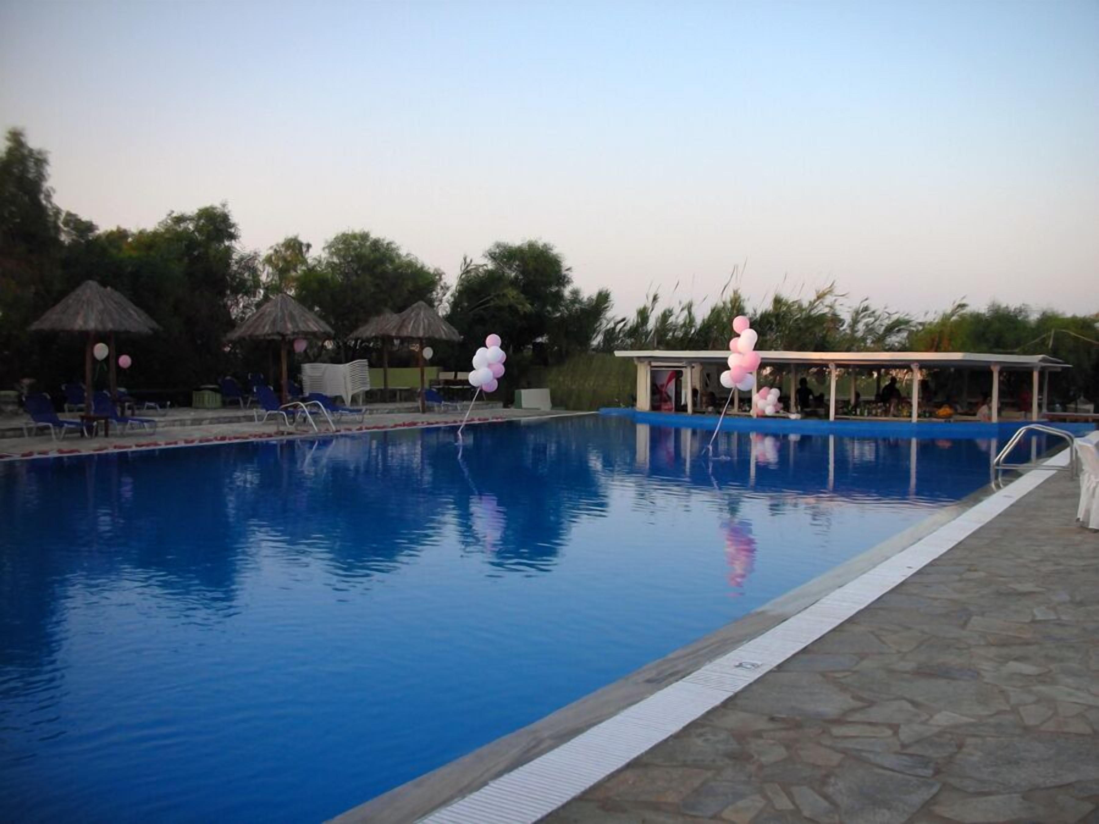 A swimming pool with lounge chairs and umbrellas, surrounded by trees.
