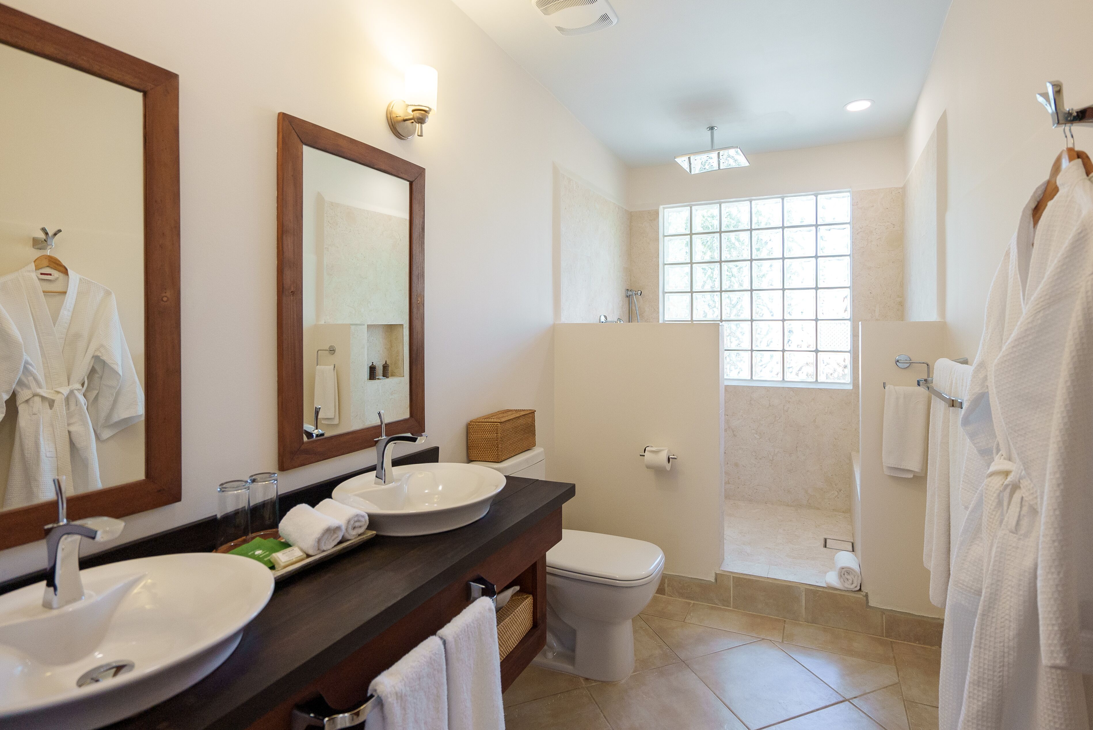 Un baño con dos lavamanos, un inodoro, una ducha y un espejo grande.