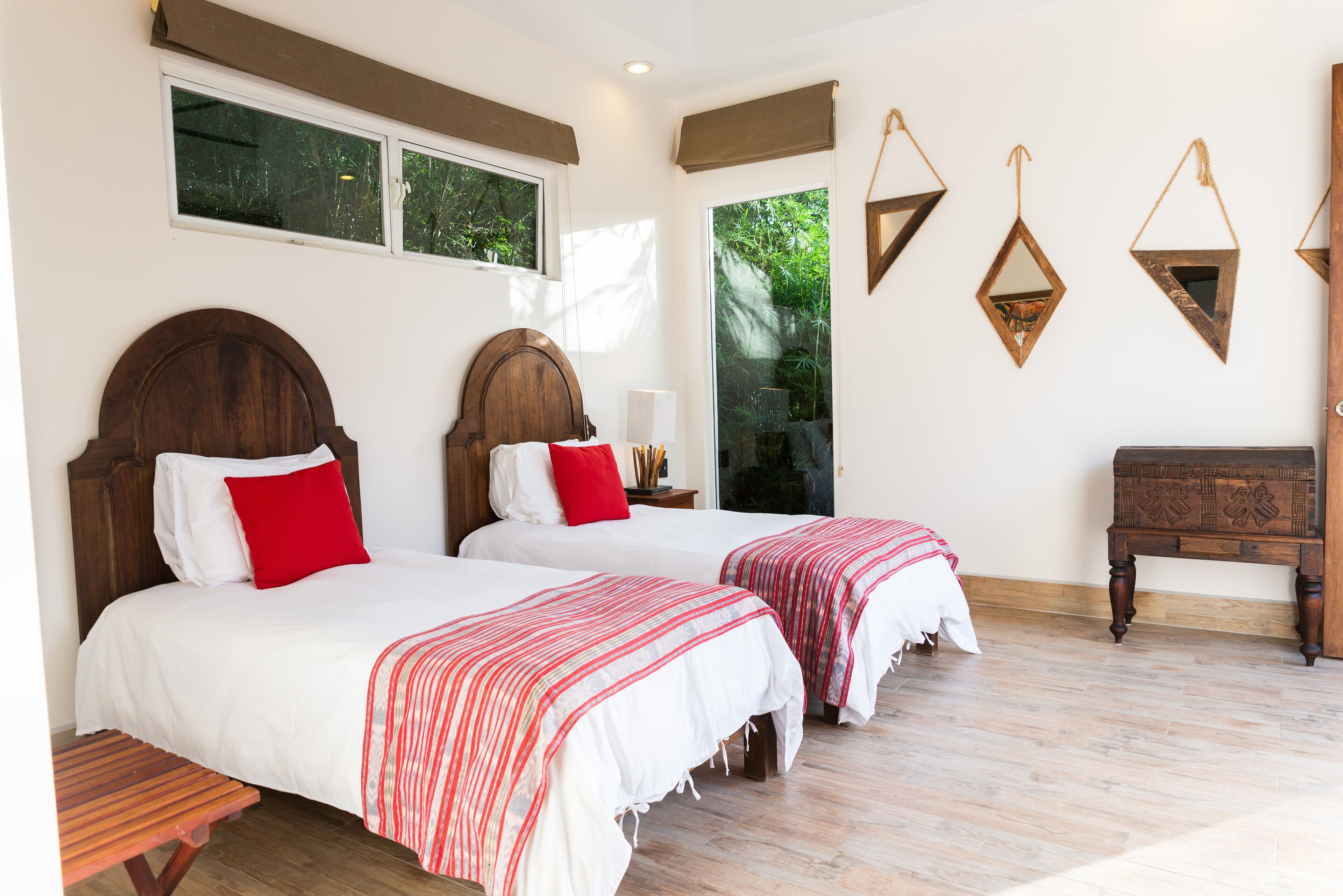 A room with two beds, a wooden headboard, a bench, and a wooden dresser.