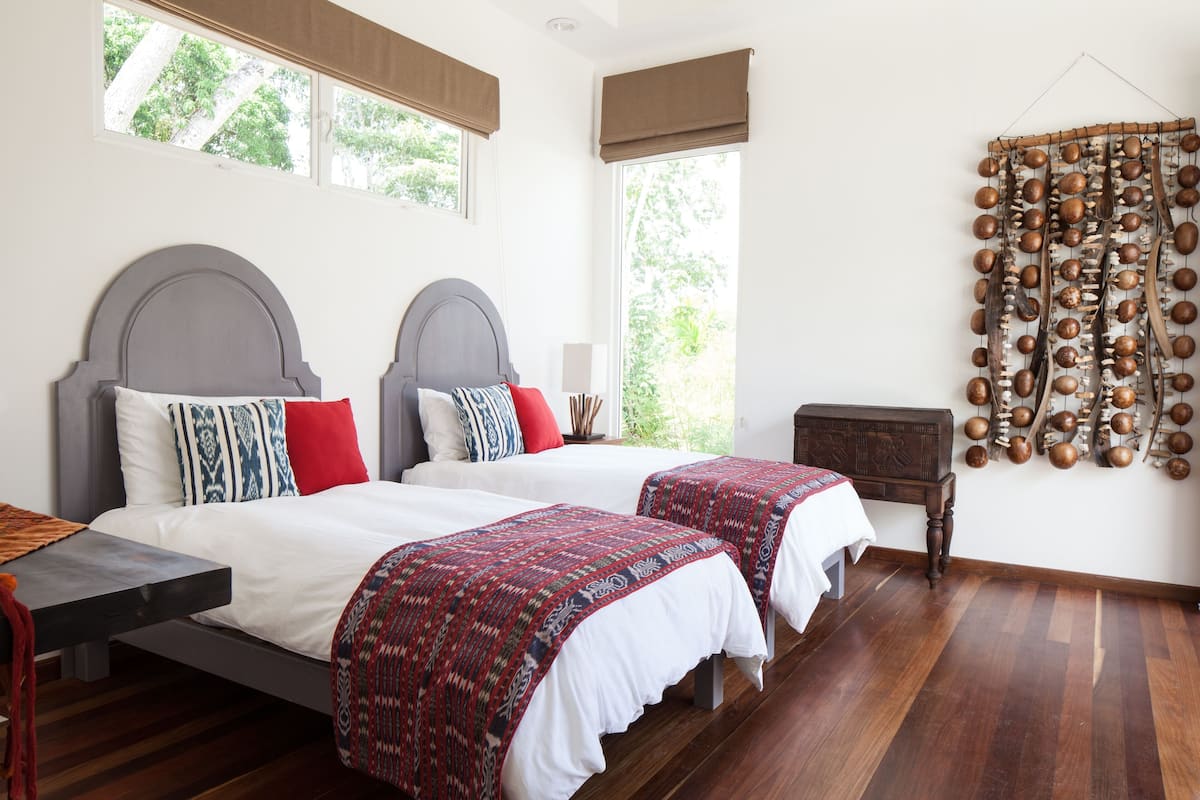 Un dormitorio con dos camas, una mesita de noche de madera y un adorno en la pared.