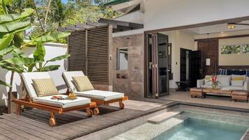 A modern outdoor pool area with lounge chairs, a wooden deck, and a view of the house.