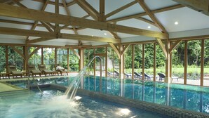 An indoor swimming pool with wooden beams, clear water, and lounge chairs. - Luton Hoo Hotel, Golf And Spa (Luton)