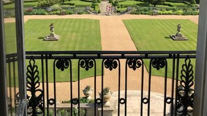 A view of a formal garden with manicured lawns, statues, and a central fountain from a balcony with ornate metal railings. - Luton Hoo Hotel, Golf And Spa (Luton)