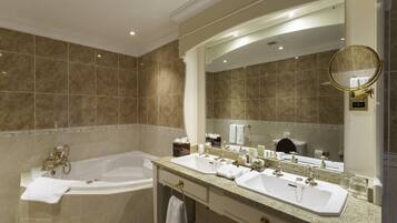 A bathroom with a bathtub, two sinks, a vanity, and a large mirror.