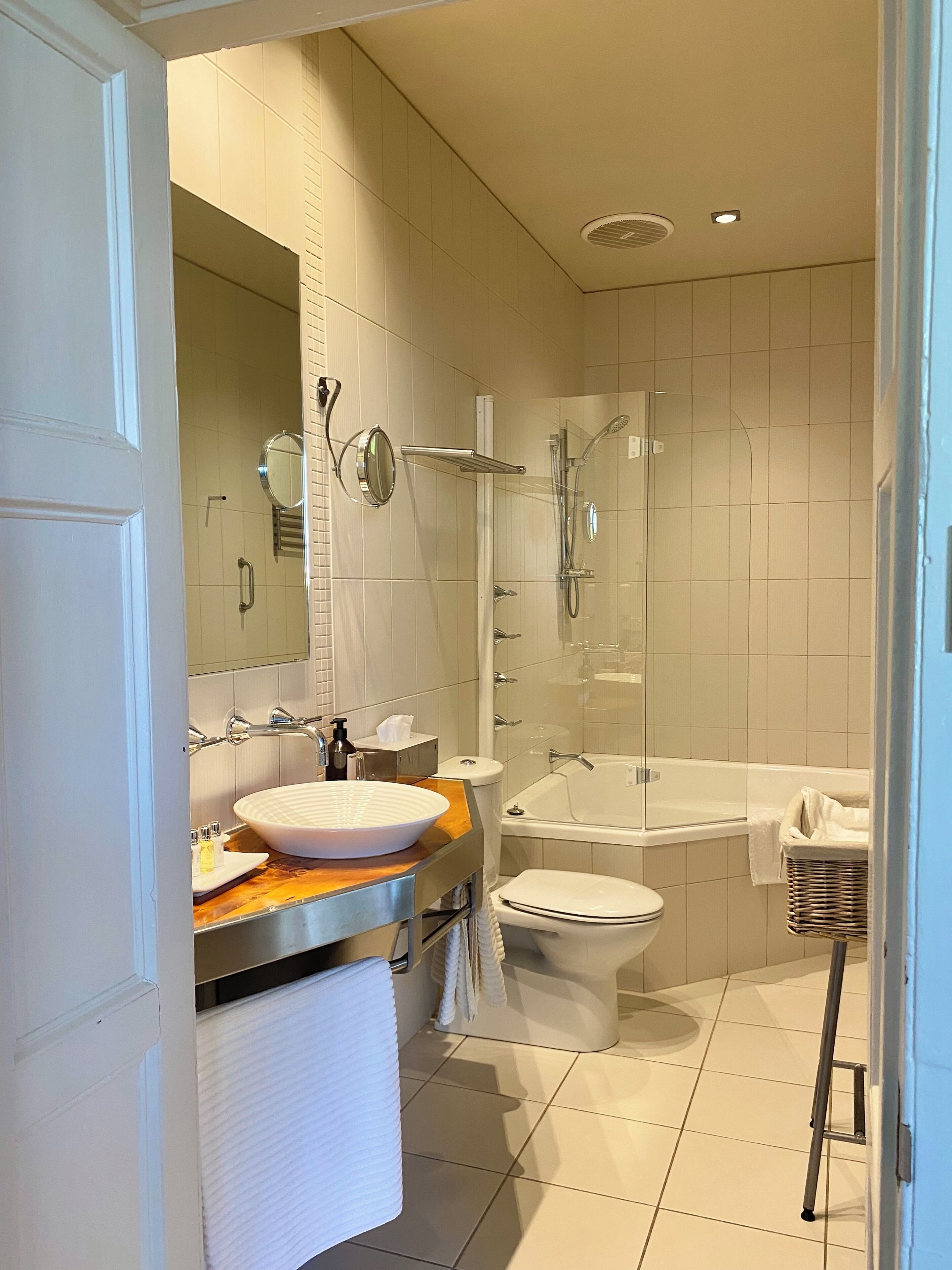 A modern bathroom with a large sink, mirror, toilet, and a glass-enclosed shower area.