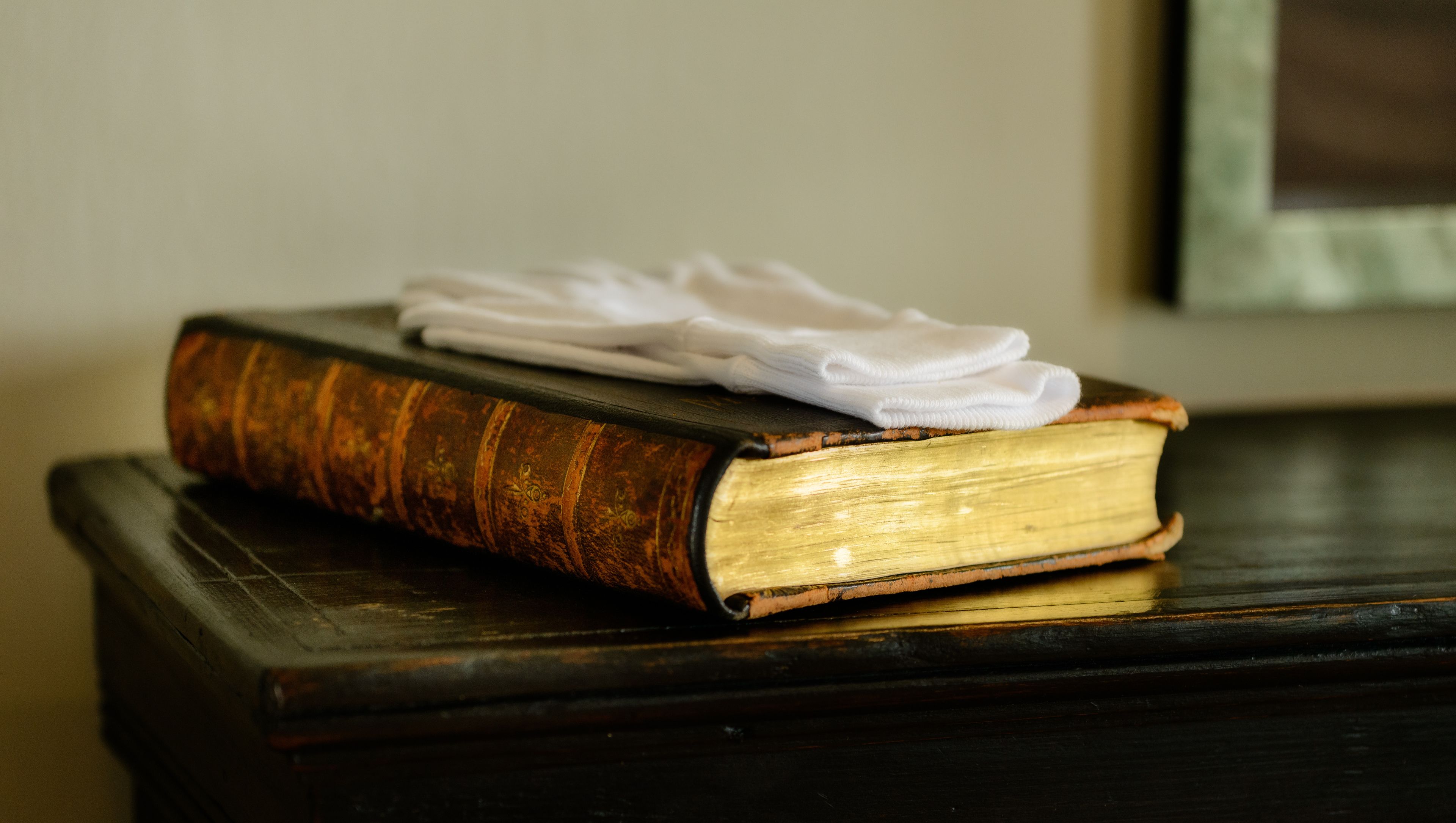 Un libro con un paño blanco encima, sobre una superficie de madera oscura.