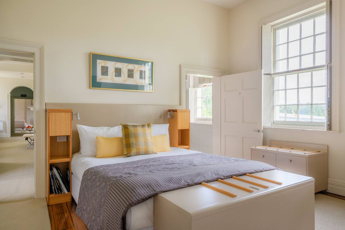 Een slaapkamer met een bed, nachtkastjes, een kledingkast, een raam en een deur.