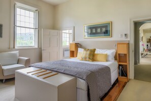 Une chambre à coucher avec un lit, des tables de chevet, une chaise et une fenêtre.