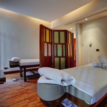 A hotel room with a bed, bedside table, lamp, and a wooden partition.