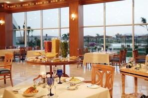 A dining area with tables set for meals, large windows, and a view of the outdoors. - Jolie Ville Royal Peninsula Hotel & Resort Sharm El Sheikh (Sharm El Sheikh)