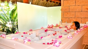 A bathtub filled with ice and pink flowers, with a person relaxing in it. - Pacífica Resort Ixtapa All-Inclusive (Ixtapa)