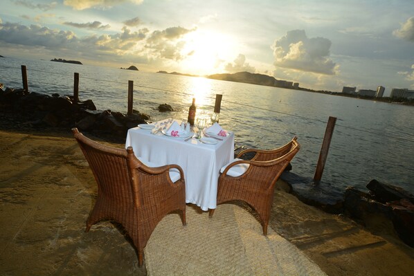 Una mesa para dos con vistas al atardecer sobre el agua.