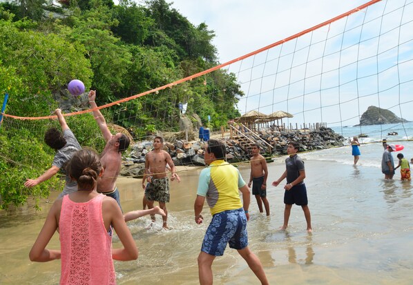 A beach volleyball game with players and spectators.