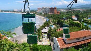 Un resort costero con un sistema de teleférico, playa y vegetación circundante.