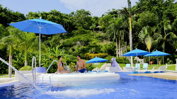 A pool area with blue umbrellas, lounge chairs, and a hot tub. - Pacífica Resort Ixtapa All-Inclusive (Ixtapa)