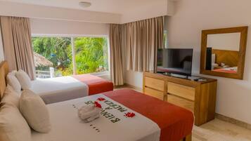 Quarto de hotel com duas camas, televisão, cómoda de madeira e uma janela grande com vista para áreas verdes.