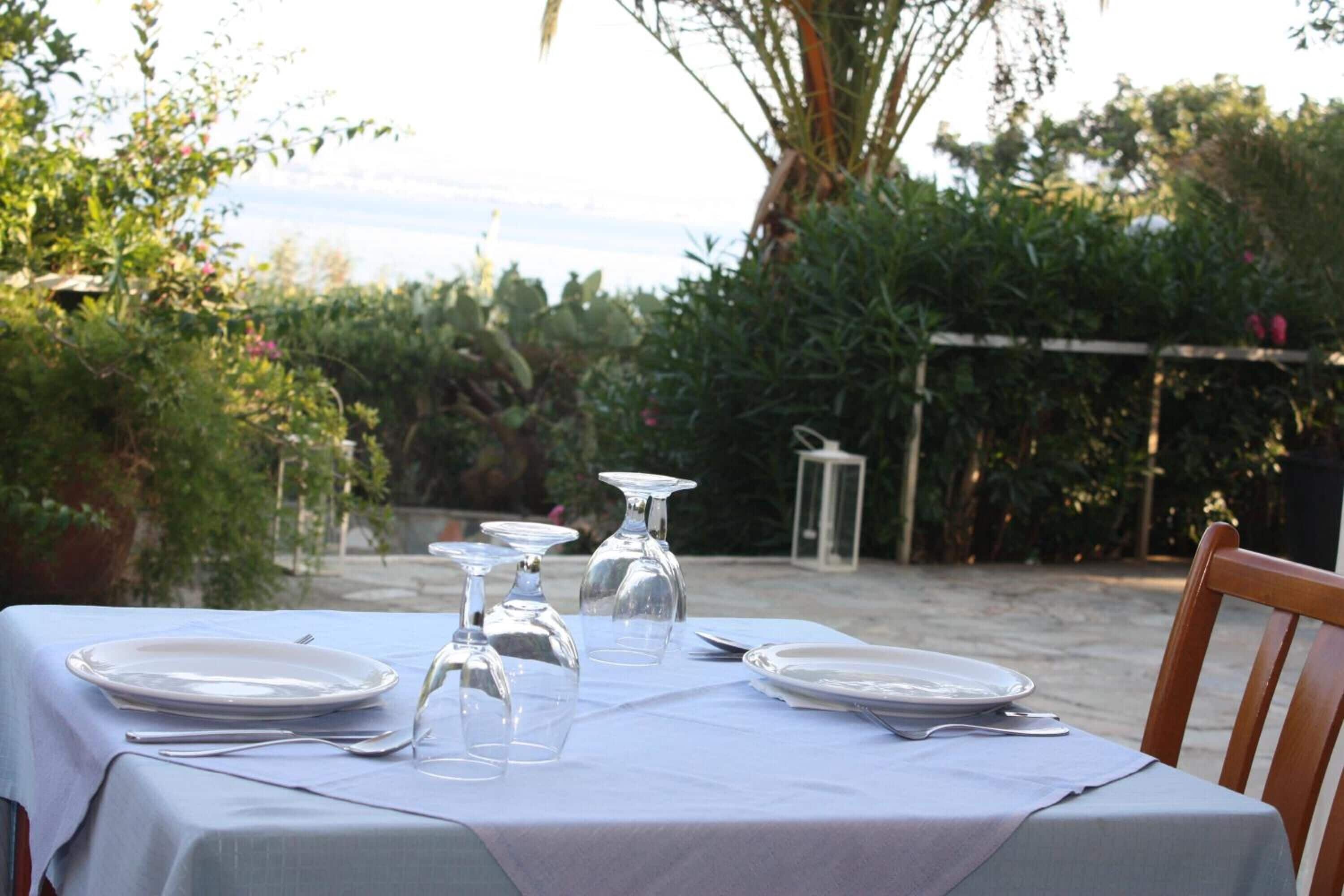 A table set outdoors with plates, glasses, and cutlery.