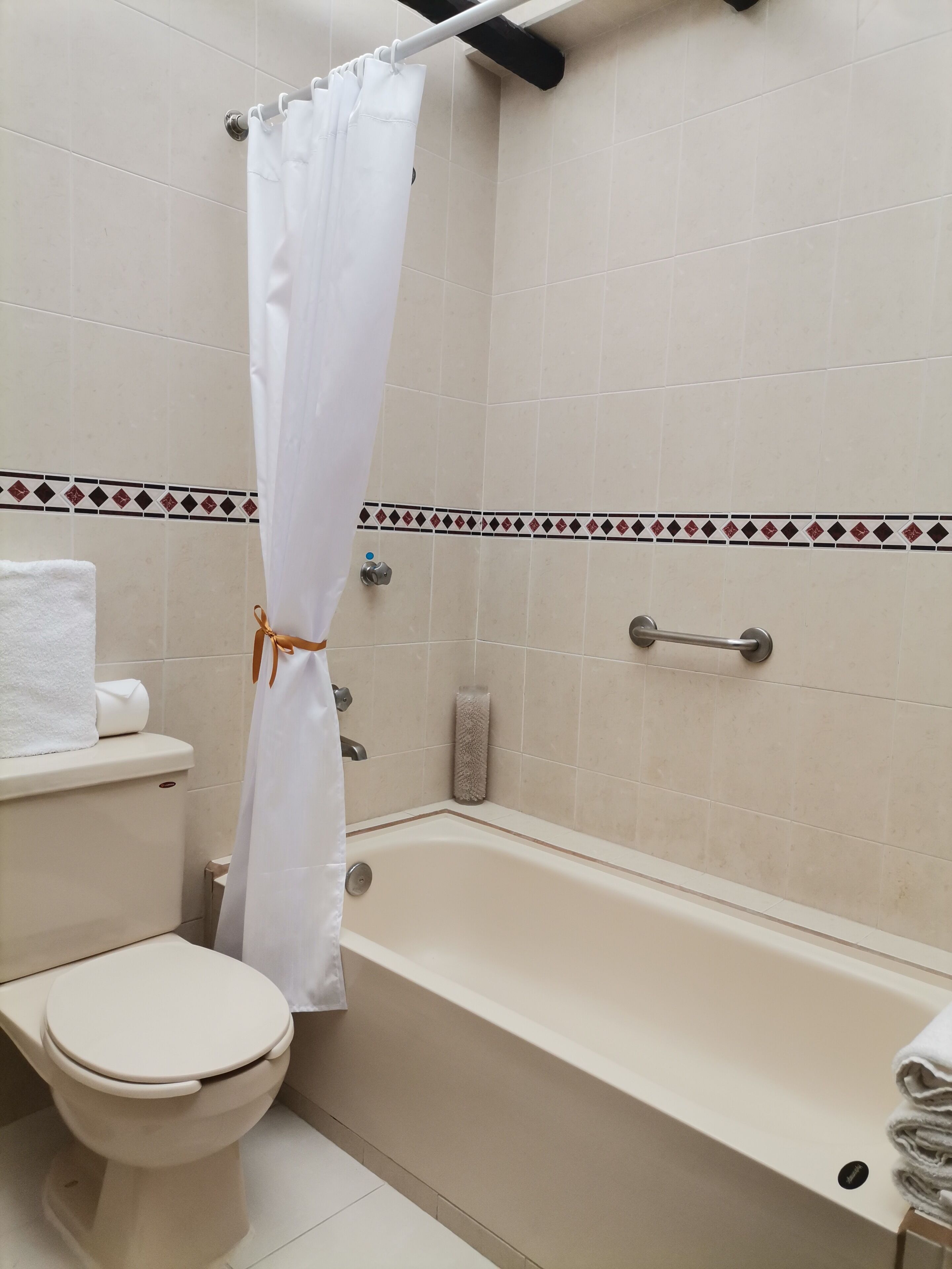 A bathroom with a bathtub, toilet, and a shower curtain.