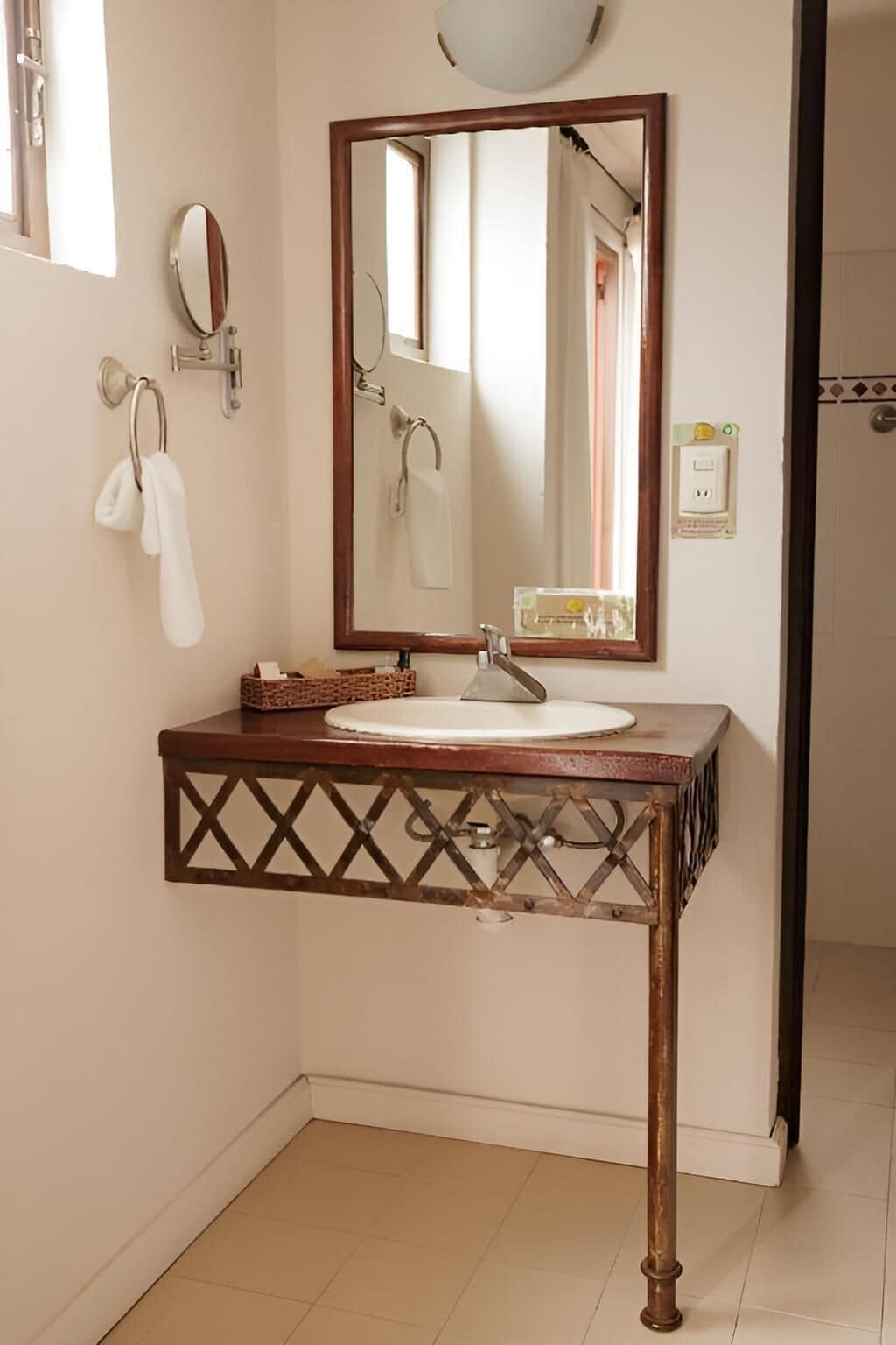 A bathroom with a wooden vanity, a round sink, a mirror, and a towel rack.