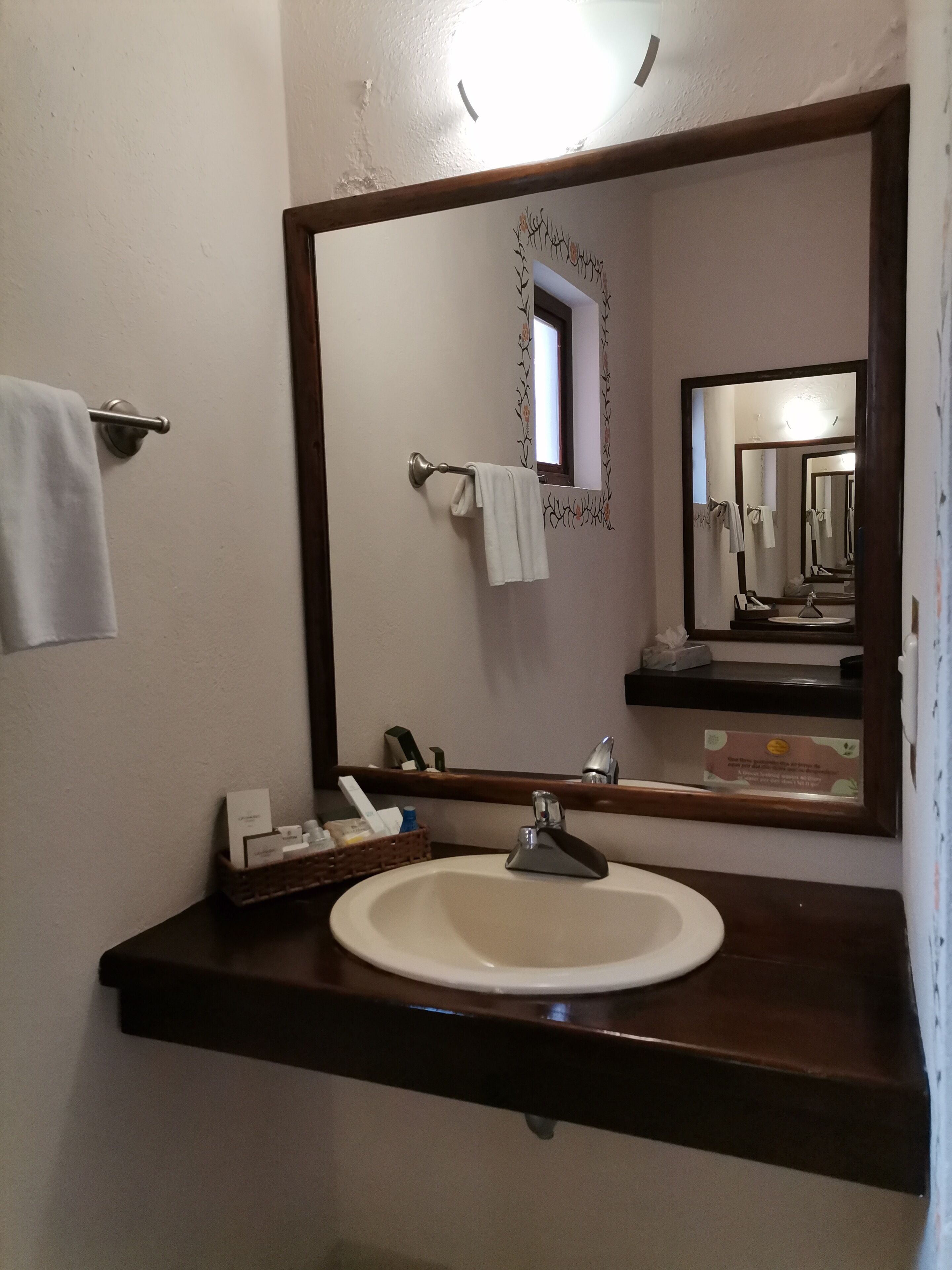 A bathroom with a large mirror, a sink, and a towel rack.